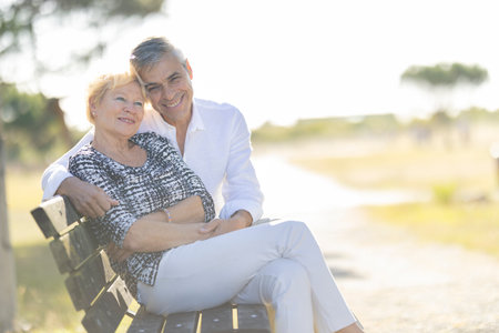 Happy senior couple relaxing on park bench embracing each otherの写真素材