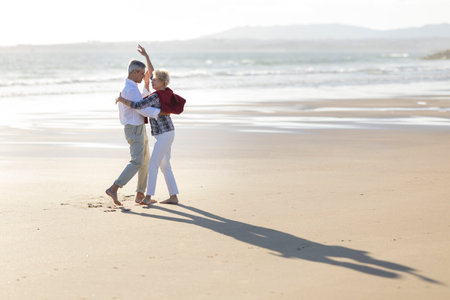 Happy retired couple dancing on a sandy beachの写真素材
