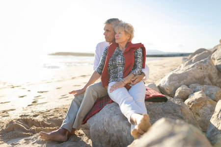 Senior couple relaxing on beach at sunset embracing each otherの写真素材