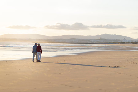 Senior couple walking on the beach at sunset, enjoying retirement