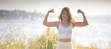 Young athletic woman showing muscles by the river in lisbon