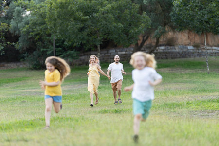 Happy family running and playing together in parkの写真素材