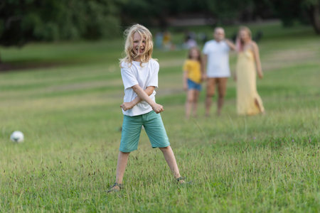 Blond boy making funny faces while playing in the park with familyの写真素材