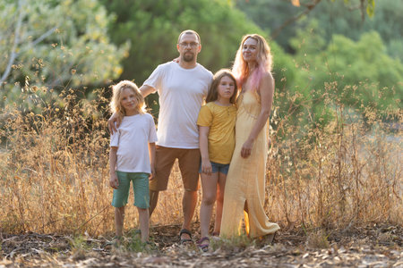 Family posing together outdoors in tall grass at golden hourの写真素材