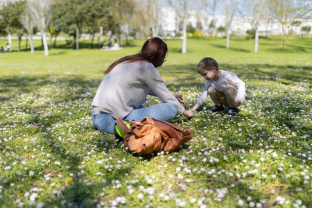 Mother and daughter picking daisies in a sunny park