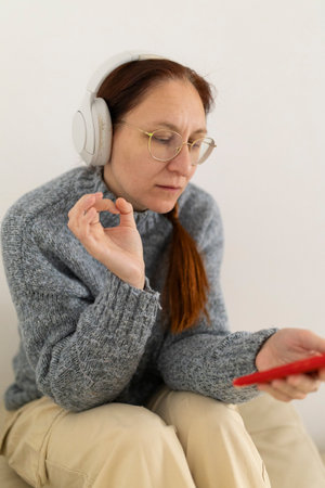 Woman listening music with headphones and making ok sign with fingersの写真素材