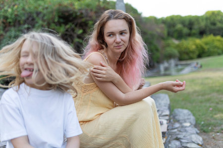 Mother and daughter sharing a moment in the park, child sticking out tongueの写真素材