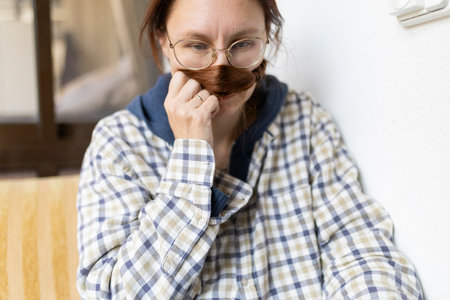 Woman making fake mustache with hair while smelling itの写真素材