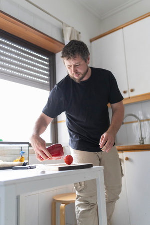 Chef placing red bell pepper and tomato on cutting board in kitchenの写真素材