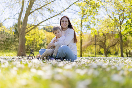 Mother embracing son in a field of flowers on a sunny spring day