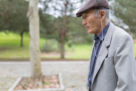Elderly man listening to music while walking in park