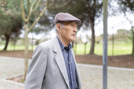 Elderly gentleman listening music walking in parkの写真素材