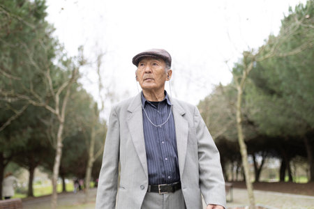 Elegant senior man listening music while walking in parkの写真素材