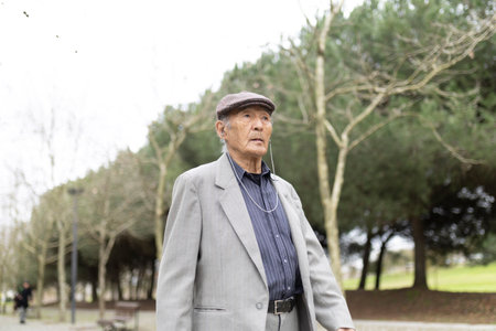Elderly asian man listening music walking in parkの写真素材