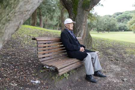 Senior man relaxing on park bench contemplating natureの写真素材