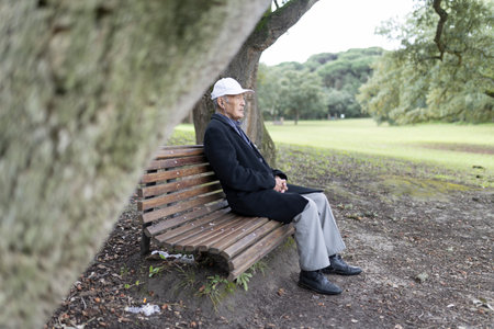 Senior man relaxing on park bench enjoying natureの写真素材