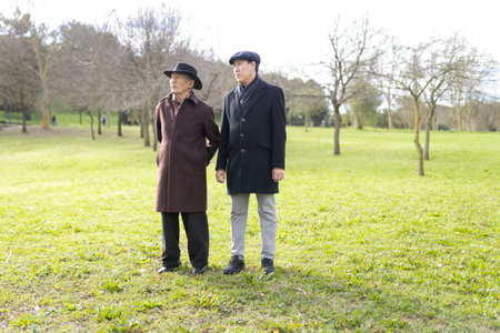 Father and son standing together in park during winter dayの写真素材
