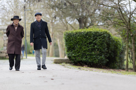 Two senior men walking in park during winterの写真素材