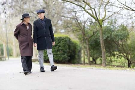 Father and son walking and talking in park during winterの写真素材
