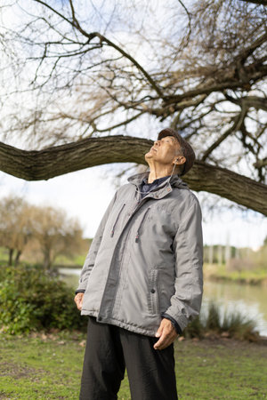 Senior man listening music enjoying nature in public park