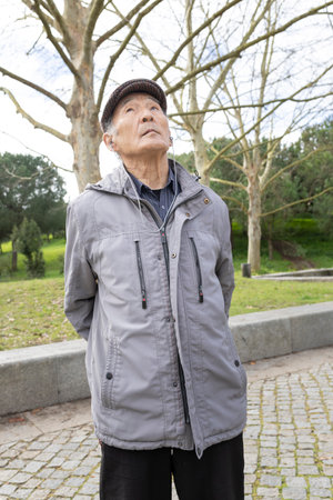 Elderly asian man listening to music in park looking upの写真素材