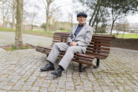 Elderly man relaxing on bench in peaceful park settingの写真素材