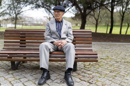 Senior man sitting on bench in park contemplating lifeの写真素材