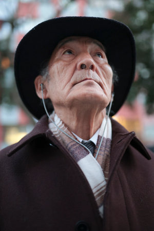 Elegant senior man wearing earphones and looking up in the cityの写真素材