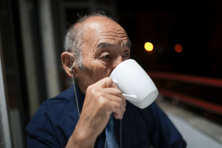 Senior businessman drinking from mug on balcony at night