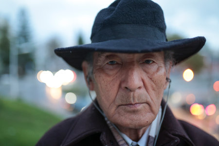 Portrait of senior man wearing hat and listening music with earphones in the cityの写真素材