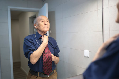 Senior businessman adjusting tie in bathroom mirrorの写真素材
