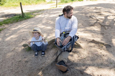 Father and son resting during hike in sunny forestの写真素材