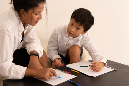 Child learning to draw with teacher using colored pencilsの写真素材