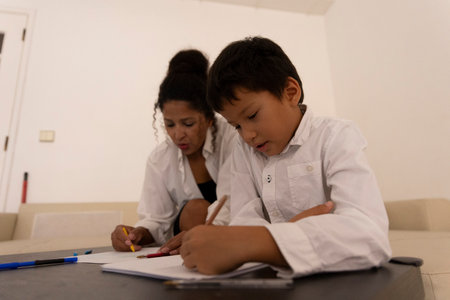 Latin american mother and son drawing together at homeの写真素材