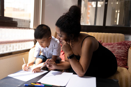 Mother helping son with homework, supporting education at homeの写真素材
