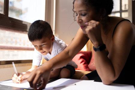 Mother helping son with homework, supporting education at homeの写真素材
