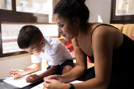 Mother helping son with homework, supporting education at homeの写真素材