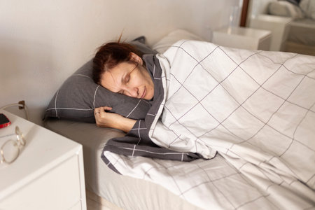 Woman sleeping peacefully in bed on checkered blanket and pillow