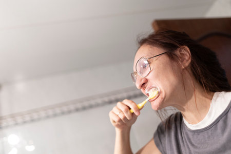 Woman brushing teeth with toothbrush and toothpaste in bathroomの写真素材