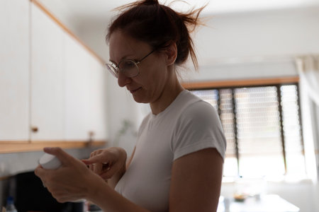 Woman reading medicine instructions in kitchenの写真素材