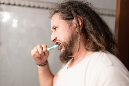 Man with dreadlocks brushing teeth in bathroom: oral hygiene routineの写真素材