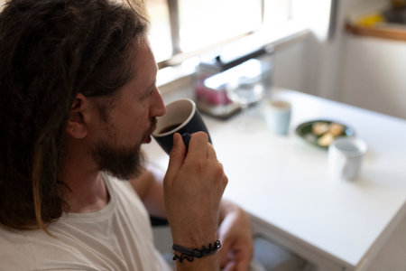 Man drinking coffee in kitchen during morning routine