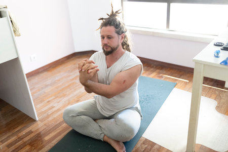 Man practicing yoga meditation at home on a matの写真素材