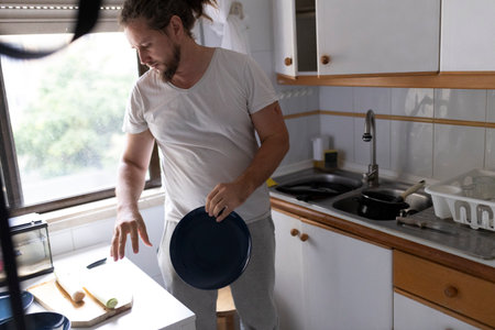 Man preparing ingredients and picking up plate in kitchenの写真素材