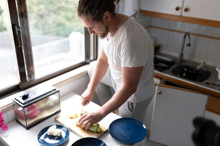 Man cutting vegetables while recording cooking show in kitchenの写真素材