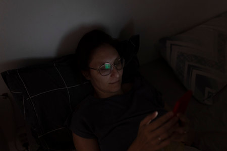 Woman using smartphone in bed at nightの写真素材