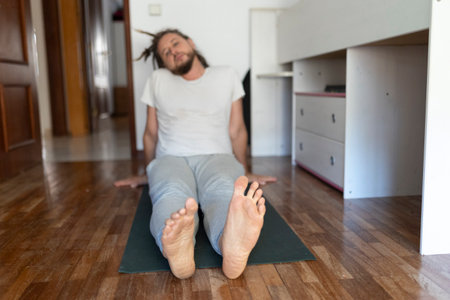 Man doing staff pose on yoga mat at homeの写真素材