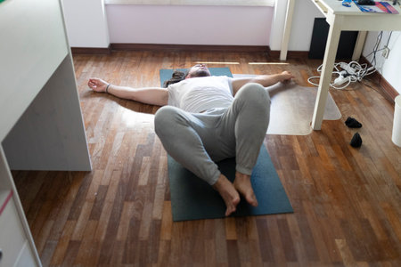 Young man relaxing on yoga mat after working from homeの写真素材
