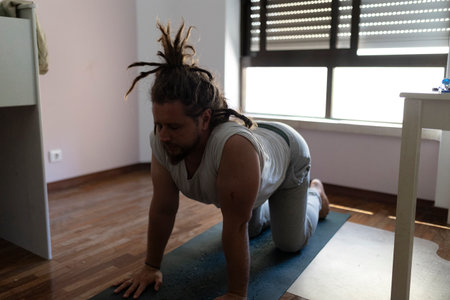 Man practicing cow pose on yoga mat at homeの写真素材