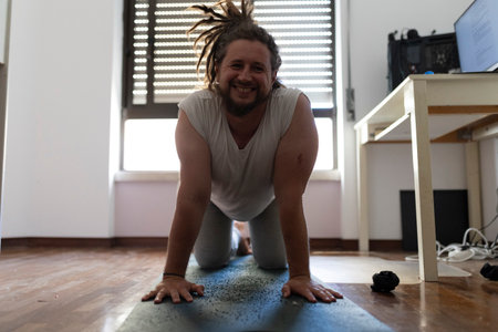 Freelancer doing yoga on mat in home officeの写真素材